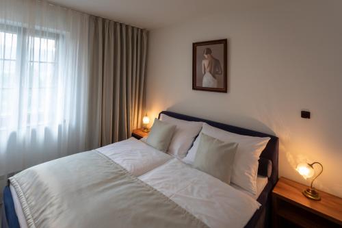 a bedroom with a bed with white sheets and a window at Hotel Zámeček Pod Hradem Starý Jičín 111 in Starý Jičín