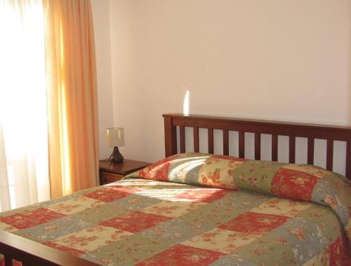 ein Bett mit einer Decke in einem Schlafzimmer in der Unterkunft Cabañas Don Gustavo in La Serena