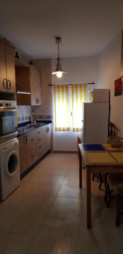 La cuisine est équipée d'une table, d'une cuisinière et d'un réfrigérateur. dans l'établissement Alojamiento Rural Jacinta, à Torres de Albanchez