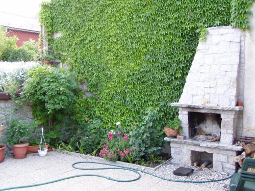 einen Garten mit einem gemauerten Kamin neben einer grünen Hecke in der Unterkunft Penzion Iga in Jindřichův Hradec