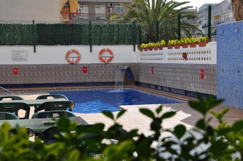 a swimming pool in a building with chairs and plants at Aparthotel Safari in Calella
