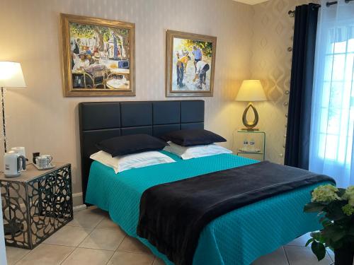 een slaapkamer met een groot bed en een blauwe deken bij CHAMBRE D'HOTES "Les Volets Bleus" - VILLA L'OLIVIER côté mer in Vaux-sur-Mer