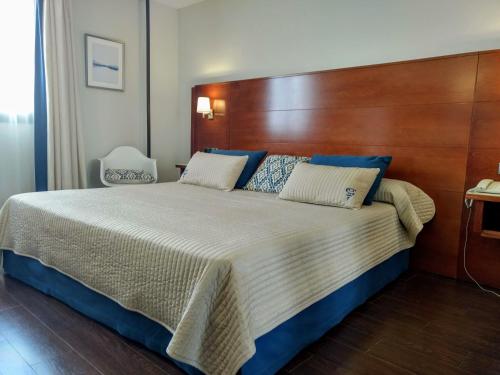 a bedroom with a large bed with a wooden headboard at Hotel Hidalgo in Esquivias