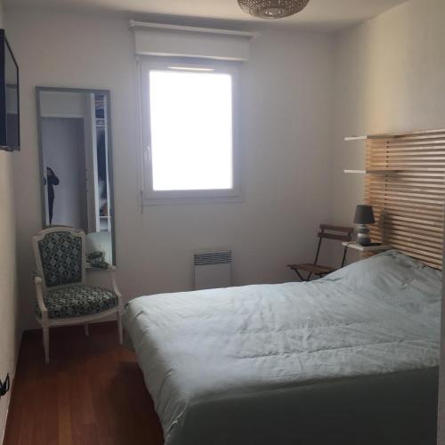 une chambre avec un lit, une chaise et une fenêtre dans l'établissement Appartement T3 classé 3 étoiles vue mer avec terrasse ,plage 2 minutes à pied, à Ajaccio