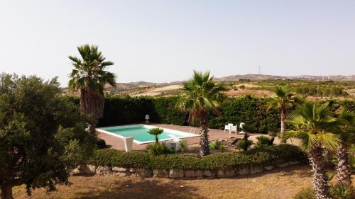 una piscina en un patio con palmeras en Borgo delle Pietre, en Porto Empedocle