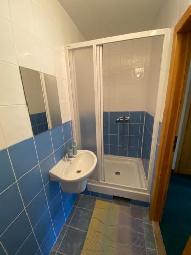 a blue and white bathroom with a sink and a shower at Penzion pod Brehom in Terchová