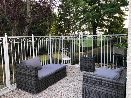two wicker chairs sitting in front of a fence at Le Clos des Moulins 2 rue des cotes de l'Héry in Hautvillers