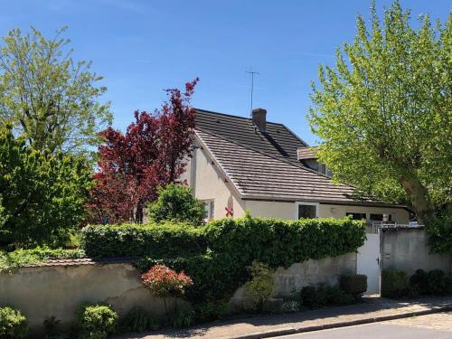 una casa blanca con techo gris y arbustos en Le Clos des Moulins, en Hautvillers