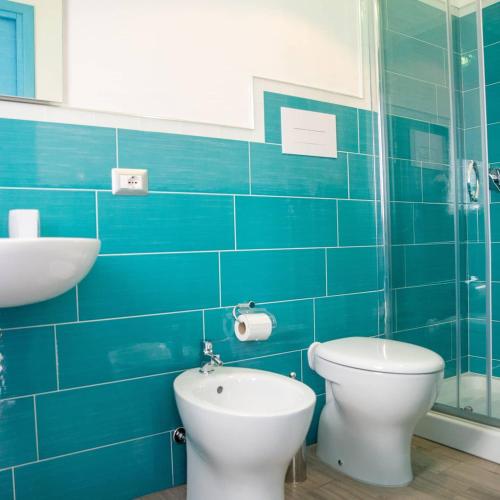 a blue tiled bathroom with a toilet and a sink at Sisinedda in Siniscola