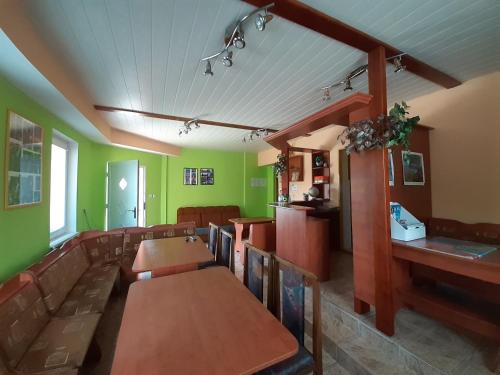 a restaurant with green walls and wooden tables and chairs at Privát Čujová in Hrabušice