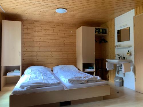 a bed in a room with a wooden wall at Pension Waldegg - restaurant in Saas-Almagell