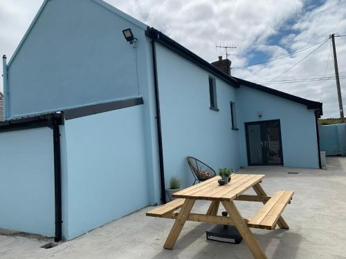 a picnic table in front of a blue building at Traditional Farm House in the Old Head of Kinsale in Cork