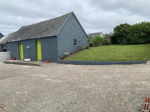 a blue house with yellow doors in a driveway at Traditional Farm House in the Old Head of Kinsale in Cork