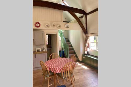 a dining room with a table and chairs and a staircase at Gorgeous comfortable barn with huge private orchard in quiet Suffolk location in Depden