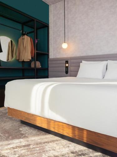 a bedroom with a large white bed and a mirror at Novotel Mexico City Toreo in Mexico City