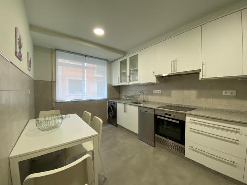 a kitchen with white cabinets and a table and chairs at Cedemar 1 in Cedeira