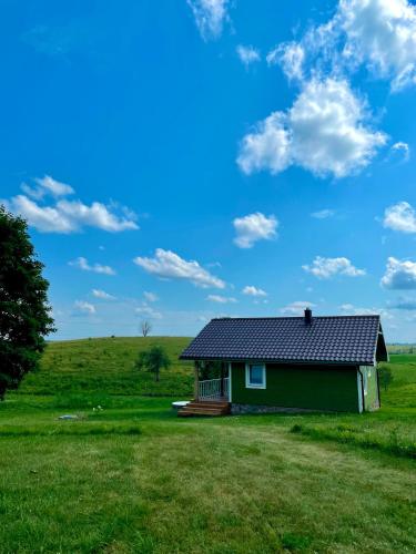 a green house in the middle of a field at ALANTOS ŽIRGAI Holiday Villas sauna or hottube additional price in Alanta