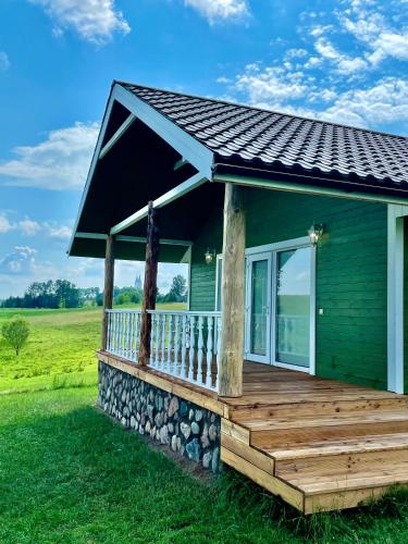 a green house with a large wooden deck at ALANTOS ŽIRGAI Holiday Villas sauna or hottube additional price in Alanta