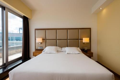 a bedroom with a large bed and a large window at Hotel Thalasso Cantabrico Las Sirenas 4 Superior in Viveiro