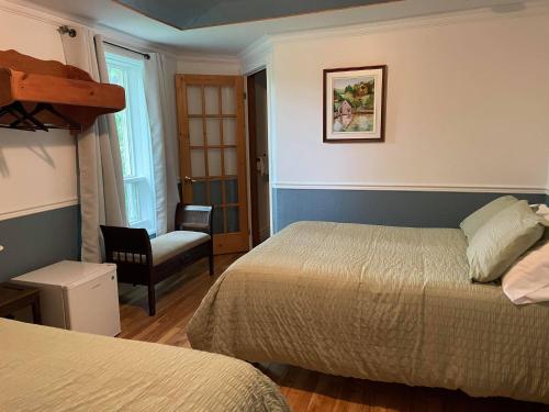 a hotel room with two beds and a chair at auberge les deux tours in Jonquiere