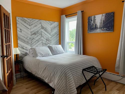 a bedroom with a bed with orange walls and a window at auberge les deux tours in Jonquiere