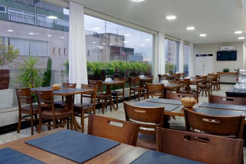 un restaurante con mesas y sillas de madera y ventanas en Fênix Hotel Bom Retiro, en São Paulo