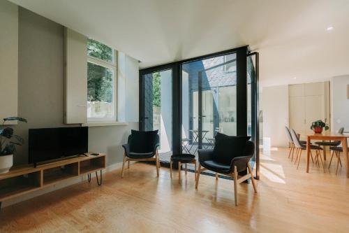 uma sala de estar com uma televisão de ecrã plano e cadeiras em Aparthotel Oporto Palace em Porto