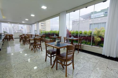 a restaurant with tables and chairs and large windows at Fênix Hotel Bom Retiro in Sao Paulo