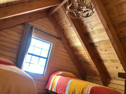 a room with wooden walls and a window and two beds at Bosques de Monterreal in Mesa de las Tablas