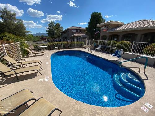 a swimming pool with chairs and a swimming pool at Pines Inn & Suites in Cottonwood