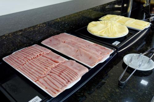 two trays of meat and cheese on a counter at Fênix Hotel Bom Retiro in Sao Paulo