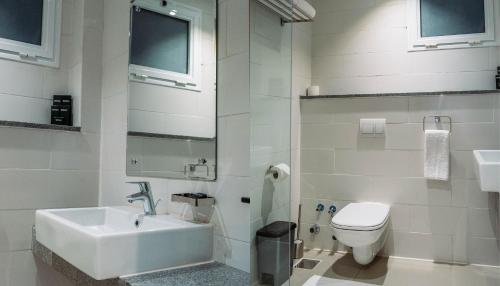 a white bathroom with a sink and a toilet at Palma Hotel in Port Said