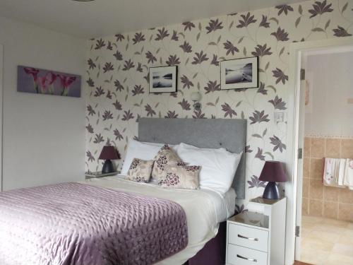 1 dormitorio con 1 cama con flores en la pared en Shepherds Lodge B&B, en Killarney