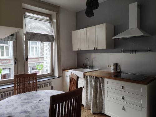 uma cozinha com armários brancos e uma mesa com cadeiras em Logies l'Epicerie de Durbuy appartement em Durbuy