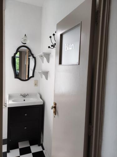 La salle de bains est pourvue d'un lavabo, d'un miroir et d'une porte. dans l'établissement Logies l'Epicerie de Durbuy appartement, à Durbuy