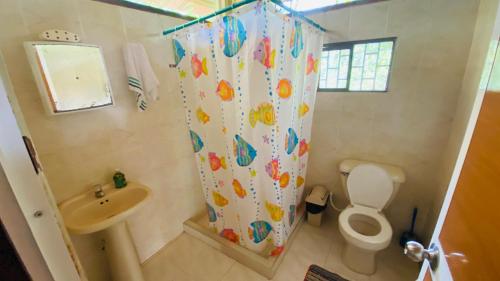 a bathroom with a shower curtain with a toilet and a sink at Ecolodge Mar y Rio in Nuquí