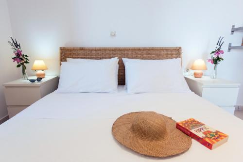 a bed with a hat and a book on it at Corfu Amboti Apt in Glyfada