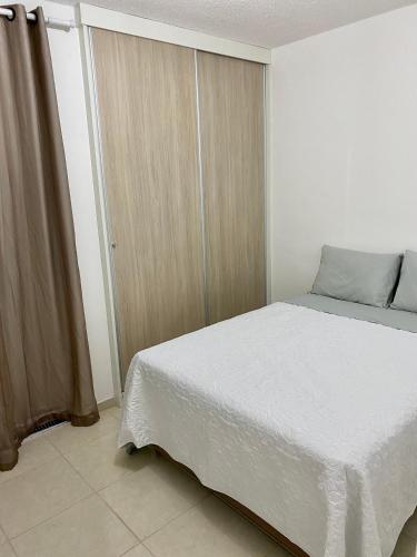 カマサリにあるApartamento Guarajubaのベッドルーム1室(白いベッド1台、スライドドア付)