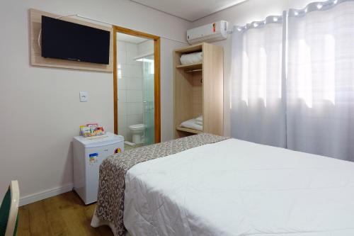 a bedroom with a bed and a bathroom with a tv at Fênix Hotel Bom Retiro in Sao Paulo