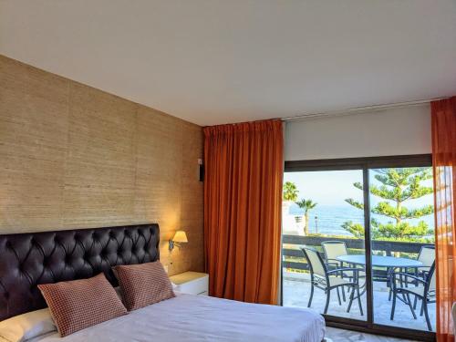 1 Schlafzimmer mit einem Bett und einem Balkon mit einem Tisch in der Unterkunft Coral Beach Aparthotel in Marbella