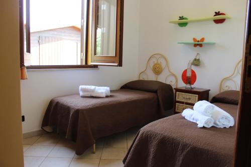 a room with two beds and a window at Casa Vacanze Libeccio - Villetta con giardino e piscina condominiale in Custonaci