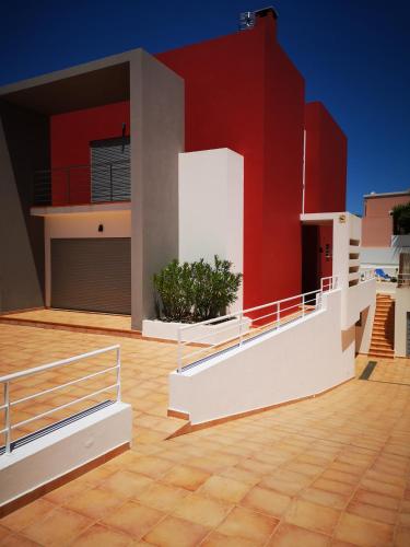 a house with a red wall and a deck at Villa Arade Ferragudo in Ferragudo