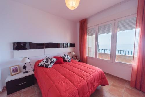 a bedroom with a red bed and a large window at Expoholidays-Ático primera línea Aguadulce in Aguadulce