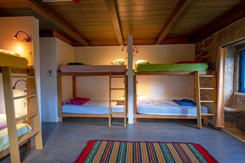 a room with three bunk beds and a rug at Quinta Estrada Romana - Albergue de Peregrinos in Cerdal