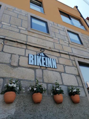 a sign on the side of a building with plants at BIKEINN in Vouzela