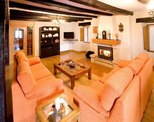 ein Wohnzimmer mit orangefarbenen Sofas und einem Kamin in der Unterkunft Casa rural ALBIRENA in Arraiz-Orquín