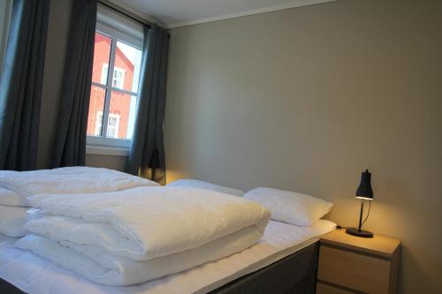 a bedroom with a bed with white sheets and a window at Setnes Feriesenter in Veblungsnes