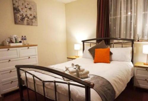- une chambre avec un lit et un oreiller orange dans l'établissement Stratton Cottage Guesthouse, à Biggleswade