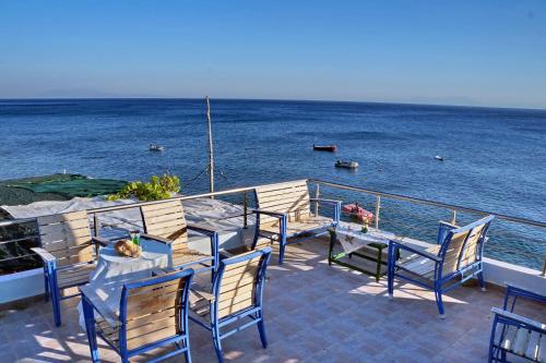 a deck with chairs and a table and the ocean at Rena's Rooms Μελίντα in Melínta