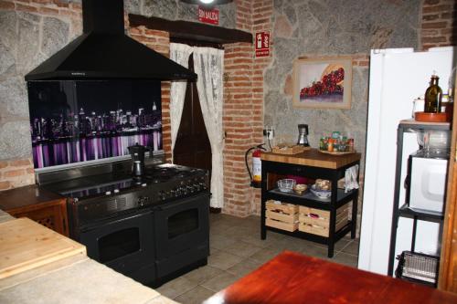 uma cozinha com fogão e uma televisão na parede em Casa Rural Puerta de Castilla em Velayos
